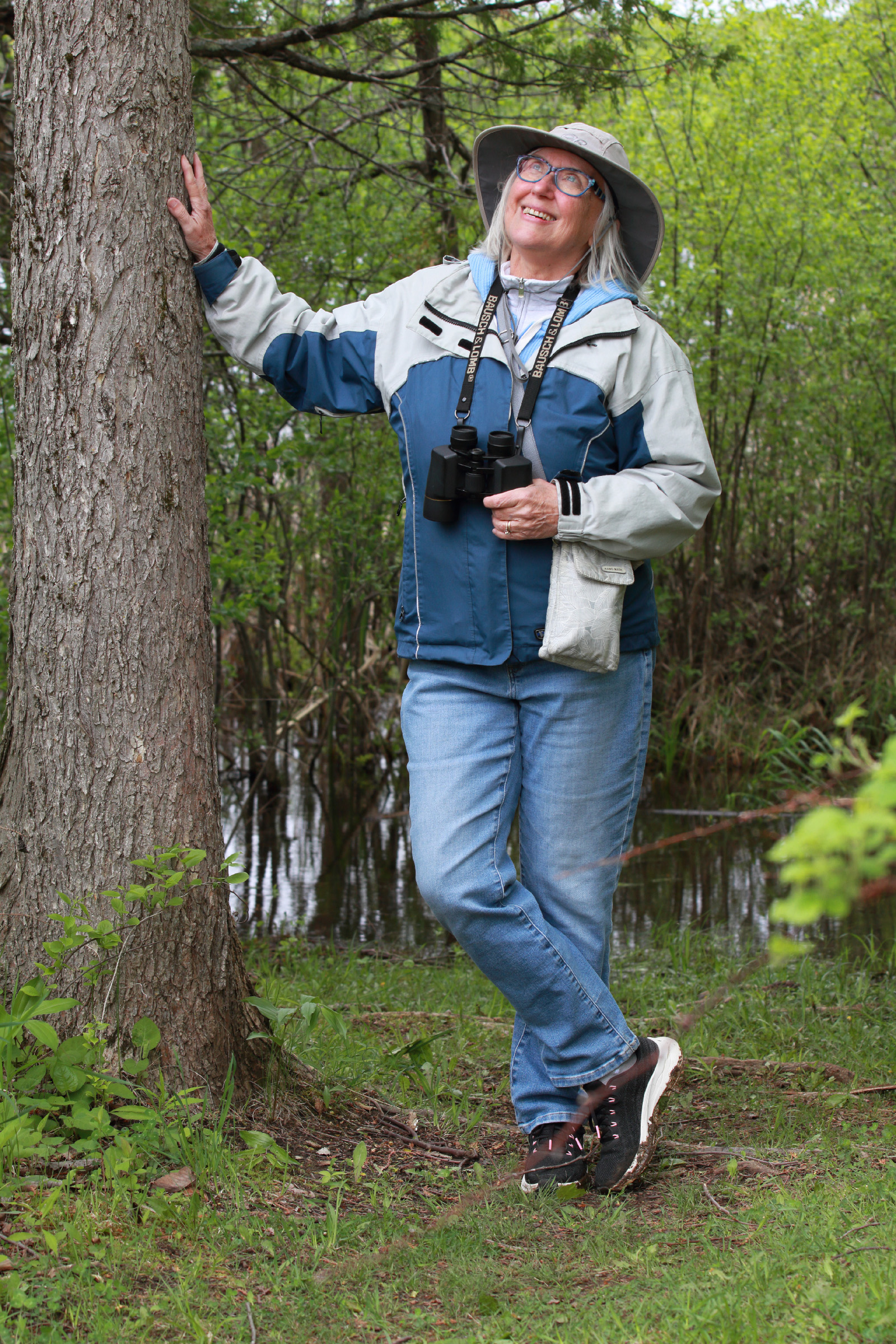 Julie in the woods beside tree